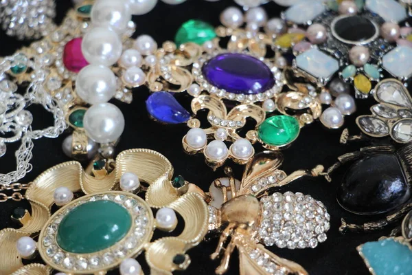 Zümrüt değerli taşlı klasik broşürler. Farklı renklerde cam ve metal broşlar. Renkli ve moda broşları. Lüks bir geçmişi var. Seçici odak