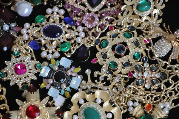 Zümrüt değerli taşlı klasik broşürler. Farklı renklerde cam ve metal broşlar. Renkli ve moda broşları. Lüks bir geçmişi var. Seçici odak