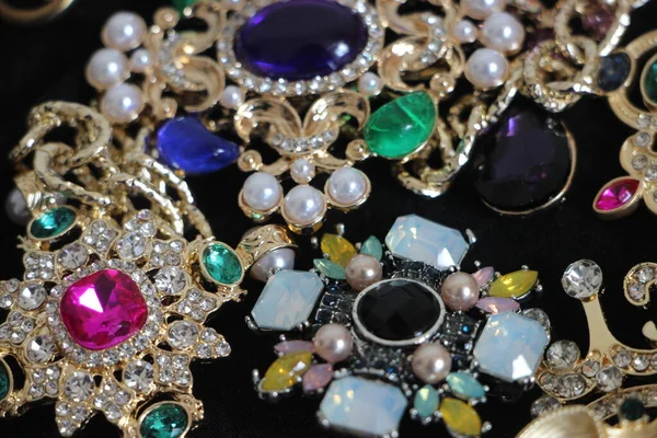 Zümrüt değerli taşlı klasik broşürler. Farklı renklerde cam ve metal broşlar. Renkli ve moda broşları. Lüks bir geçmişi var. Seçici odak