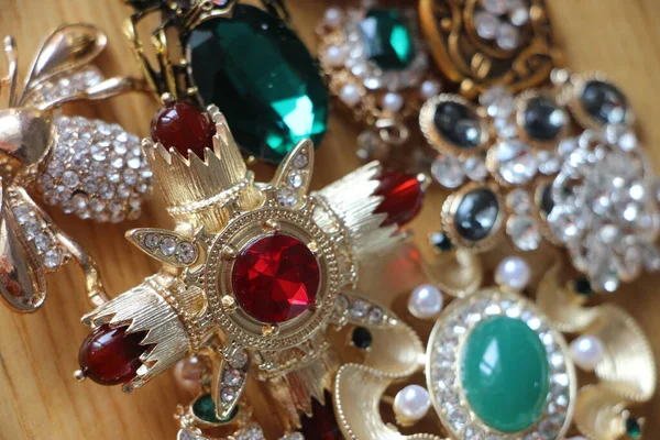 Zümrüt değerli taşlı klasik broşürler. Farklı renklerde cam ve metal broşlar. Renkli ve moda broşları. Lüks bir geçmişi var. Seçici odak