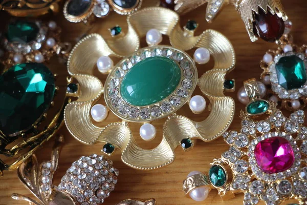 Zümrüt değerli taşlı klasik broşürler. Farklı renklerde cam ve metal broşlar. Renkli ve moda broşları. Lüks bir geçmişi var. Seçici odak