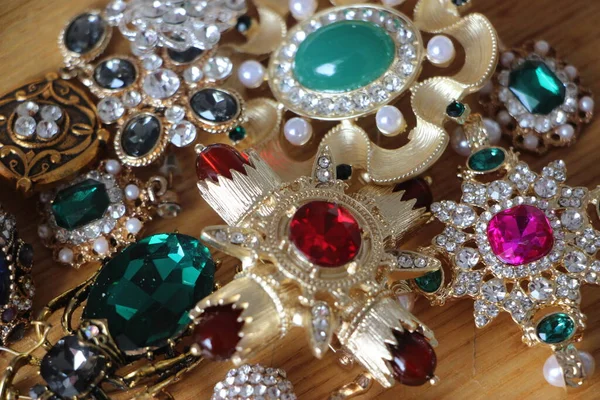 Zümrüt değerli taşlı klasik broşürler. Farklı renklerde cam ve metal broşlar. Renkli ve moda broşları. Lüks bir geçmişi var. Seçici odak
