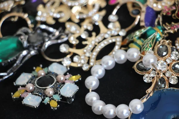 Zümrüt değerli taşlı klasik broşürler. Farklı renklerde cam ve metal broşlar. Renkli ve moda broşları. Lüks bir geçmişi var. Seçici odak