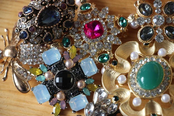 Zümrüt değerli taşlı klasik broşürler. Farklı renklerde cam ve metal broşlar. Renkli ve moda broşları. Lüks bir geçmişi var. Seçici odak