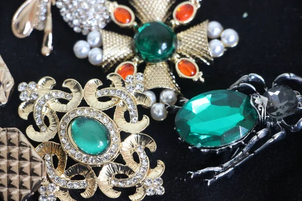 Zümrüt değerli taşlı klasik broşürler. Farklı renklerde cam ve metal broşlar. Renkli ve moda broşları. Lüks bir geçmişi var. Seçici odak