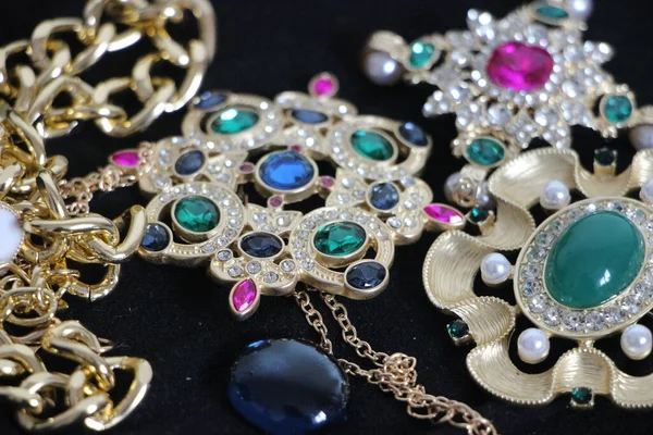 Zümrüt değerli taşlı klasik broşürler. Farklı renklerde cam ve metal broşlar. Renkli ve moda broşları. Lüks bir geçmişi var. Seçici odak