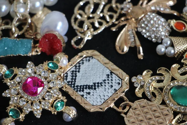 Zümrüt değerli taşlı klasik broşürler. Farklı renklerde cam ve metal broşlar. Renkli ve moda broşları. Lüks bir geçmişi var. Seçici odak