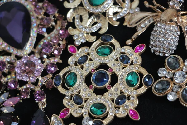 Zümrüt değerli taşlı klasik broşürler. Farklı renklerde cam ve metal broşlar. Renkli ve moda broşları. Lüks bir geçmişi var. Seçici odak