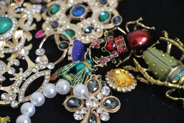 Zümrüt değerli taşlı klasik broşürler. Farklı renklerde cam ve metal broşlar. Renkli ve moda broşları. Lüks bir geçmişi var. Seçici odak