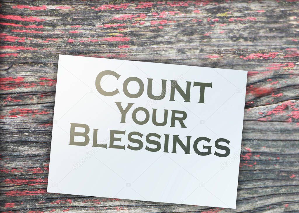 The phrase Count Your Blessings typed on a piece of paper and paper dollar signs around. Career concept.