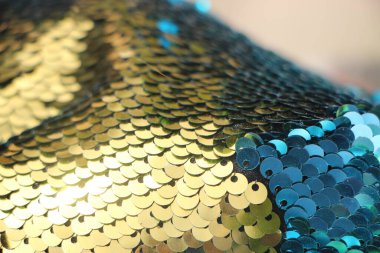 Yanıp sönen ışıklarla birlikte soyut parıltı dokusu. Mavi ve altın arkaplanlı kumaş pullar.