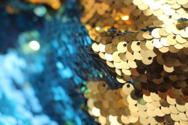 Yanıp sönen ışıklarla birlikte soyut parıltı dokusu. Mavi ve altın arkaplanlı kumaş pullar.