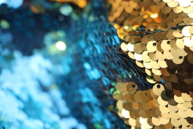 Yanıp sönen ışıklarla birlikte soyut parıltı dokusu. Mavi ve altın arkaplanlı kumaş pullar.