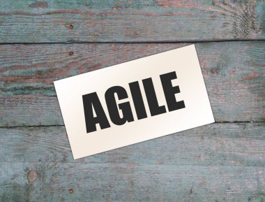 Kağıt kartvizitte AGILE yazılı, ahşap arka planda yakın plan. İş Konsepti