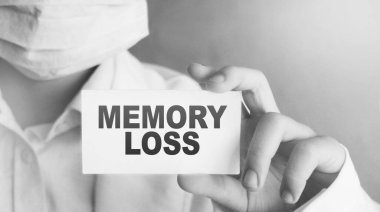 Doktor elinde hafıza kaybı tıbbi konsepti olan bir kart tutuyor..