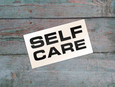 Tahta arka planda kişisel bakım metni var. Sağlık sigortası konsepti. Evde kal. Güvende kal.