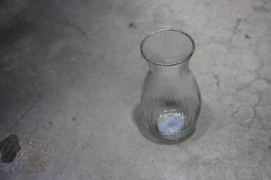 Gri arkaplanda yansıması olan boş bir cam şişe.