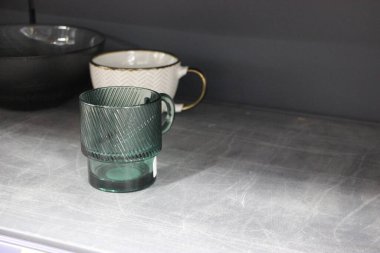 Yeşil çay demliğinin yakın plan fotoğrafı ve siyah arka planda siyah bir sapı var.