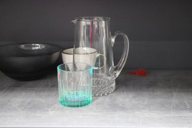 Boş cam kavanoz ve gri zemin üzerinde su olan bardak.