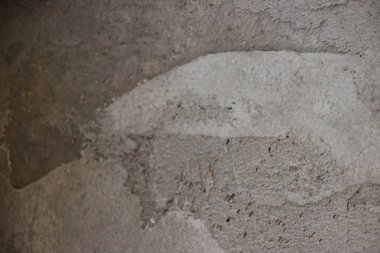 Görünür yamaları olan gri desenli beton duvar ve yüzeydeki pürüzsüzlük çeşitleri.