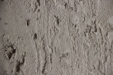 Görünür desenleri ve yüzeyde ince varyasyonları olan desenli gri alçı duvarın yakın çekimi.