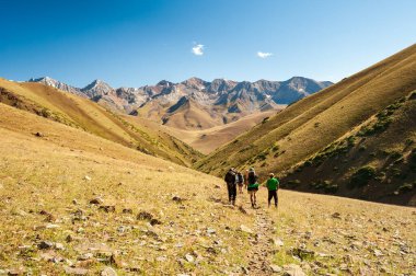 Bir grup genç yürüyüşçü dağlarda yürüyüş yapıyor. Yazın Sary Chelek Gölü, Sary-Chelek Celal Abad bölgesi, Kırgızistan, Orta Asya 'da seyahat eden iki erkek sırt çantasıyla geziyorlar..
