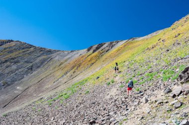 Bir grup genç yürüyüşçü dağlarda yürüyüş yapıyor. Yazın Sary Chelek Gölü, Sary-Chelek Celal Abad bölgesi, Kırgızistan, Orta Asya 'da seyahat eden iki erkek sırt çantasıyla geziyorlar..