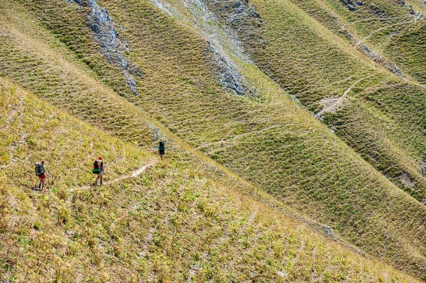 Group of young hikers trekking in mountains. Two women two men backpacking in summer near Sary Chelek lake, Sary-Chelek Jalal Abad region, Kyrgyzstan, Trekking in Central Asia.