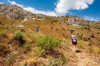 Bir grup genç yürüyüşçü dağlarda yürüyüş yapıyor. Yazın Sary Chelek Gölü, Sary-Chelek Celal Abad bölgesi, Kırgızistan, Orta Asya 'da seyahat eden iki erkek sırt çantasıyla geziyorlar..