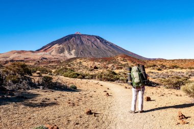Sırt çantalı genç bayan yürüyüşçü El Teide Ulusal Parkı 'ndaki Pico del Teide dağına bakıyor. Tenerife, Kanarya Adaları, İspanya