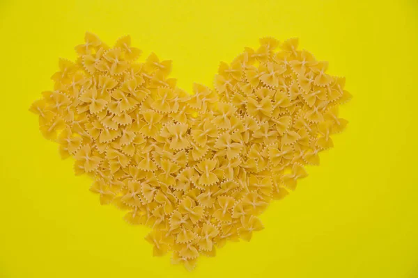 Les produits Macaroni sont dispersés sous la forme d'un cœur sur un fond jaune. — Photo