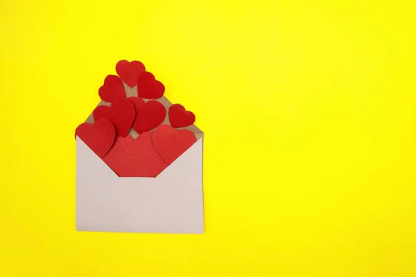 선물받은 날 선물로 봉투 안에 크기가 다른 종이 심장을 노란 백그라운드 위에 올려 놓는다.. — 스톡 사진