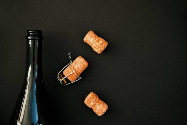 Siyah arka planda bir şişe şampanya ya da şarap. Şişenin mantarı yanında duruyor. Tatil için bir içki. Arkaplan ve doku.