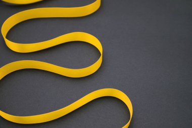 Siyah bir arka planda, sarı saten bir kurdele. Kaset bendlerle birlikte. Hediye paketi. 8 Mart ve Sevgililer Günü konsepti. Bir tebrik kartı..