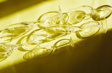 Sarı arka planda boş bardaklar, üst manzara. Güneş ışığı camın içinden kırılıyor..