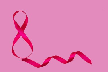 Pembe arka planda, sekiz şeklinde pembe saten bir kurdele. Hediye paketi. 8 Mart ve Sevgililer Günü konsepti. Bir tebrik kartı..