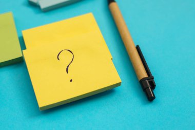 Farklı boyutlarda ve renklerde çıkartmalar mavi arka plana yerleştirilir. Yanında bir kalem var..