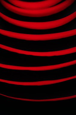 Kestane rengi saten kurdele siyah bir zemin üzerinde spiral şeklinde daireler çiziyor. Soyut arkaplan. Sonsuz bir çizgi, daireler çiziyor..