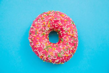 Mavi arka planda pembe bir çörek. Tatlı atıştırmalık Donut yakın çekim.