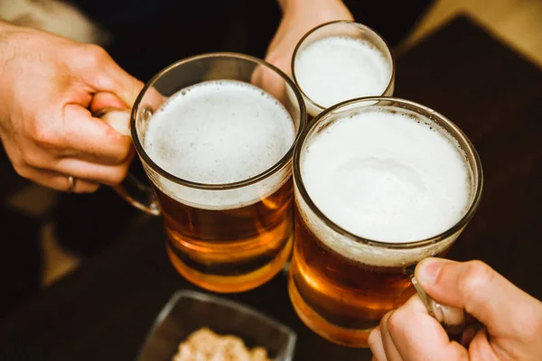 Three mugs of beer. Alcoholic drink made from wheat. Beautiful foam and bubbles on the beer.