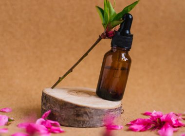 Göz damlası olan bir kabın içindeki kozmetik yağı kesilmiş bir ağaçtan yapılmış bir podyumda duruyor. Aroma terapi için temel yağ. Doğal maddelerin bileşimi.