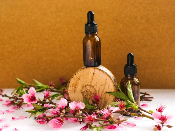 Göz damlası olan bir kabın içindeki kozmetik yağı kesilmiş bir ağaçtan yapılmış bir podyumda duruyor. Aroma terapi için temel yağ. Doğal maddelerin bileşimi.