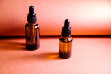 İki şişe koyu cam kozmetik yağ standı ve katlanır pembe kağıt. Yüz ve vücut bakımı. Kuaförde ve evde güzellik tedavileri. Alternatif tıp.