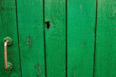 Ahşap tahtalar yeşile boyanmış. Sert ve çatlak bir yüzey. Eski ahşap ve boya. Kırsalda bir kapı. Arka plan ve doku..