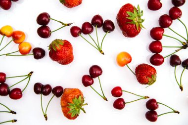 Kırmızı ve sarı olgun kiraz ve çilek. Böğürtlenler beyaz arka plana rastgele dağılmış. Sulu meyvelerin yaz arkaplanı.