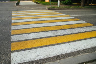 Şehrin caddesinde yaya geçidi, yaya geçidi zebrası karşıya geçerken yolda yürüyen insanların güvenliği için. Gri asfaltta sarı ve beyaz çizgiler.