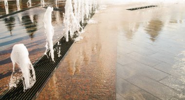 Şehir parkındaki çeşme. Yerdeki ızgaranın altından bir su fışkırıyor. Yazın çocukların eğlencesini canlandırıyor..