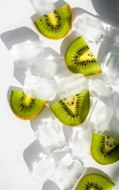 Beyaz arka planda buz küpleri ve kivi dilimleri. Güneş ışığı buzun içinde kırılır. Güzel yaz arkaplanı.