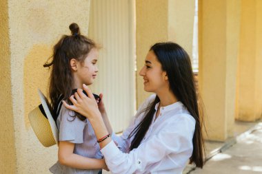 Güzel bir genç kadın küçük kızının saçını düzeltir. Aile eğlencesi ve eğlence. Anne bakımı ve sevgi. Anneler Günü ve 8 Mart.