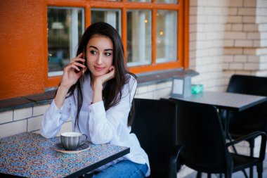 Genç ve güzel bir kız arkadaşlarıyla ya da akrabalarıyla cep telefonunda konuşuyor. Mutlu bir kadın akıllı telefonunu arkadaşlarını ve ailesini aramak için kullanır. Bir kız kahve dükkanında kahve içer..